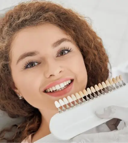 Woman dental patient smiling while the dentist is checking the teeth colour shade