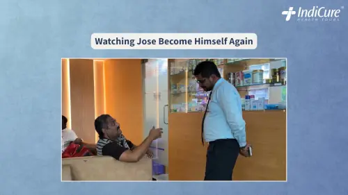 Jose Oliveria Dias sitting on a couch, smiling and gesturing warmly while conversing with a hospital staff member in a well-lit reception area.